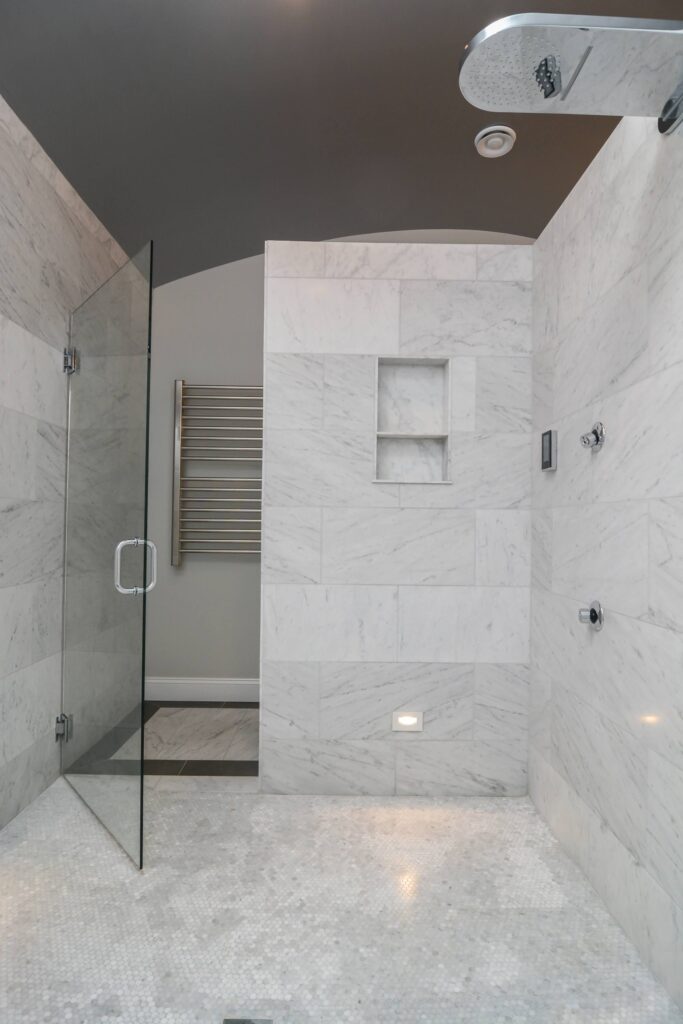 White Carrara Marble Bathroom with vaulted rounded ceiling painted mettalic gray. Kohler DTV system